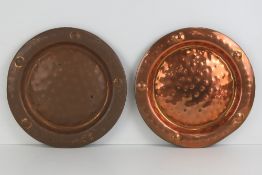A pair of decorative planished copper plates each measuring 29cm dia. Total weight 1kg.