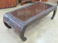 An Oriental hardwood low tea table having single drawer, part carved design upon with inswept legs,