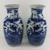 A pair of oversize blue and white Chinese shoulder vases having mythical beast design upon,