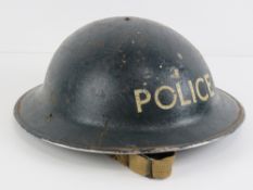 A WWII British Police helmet having liner and chin strap.