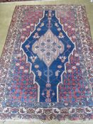 A vintage hand knotted rug in reds and blues having geometric decoration and measuring 196 x 135cm.