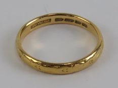 A 22ct gold ring having floral engraving throughout, hallmarked London, size M, 2.8g.