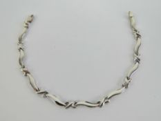 A 9ct white gold atriculated bracelet having cross and wave design panels, 19cm in length,