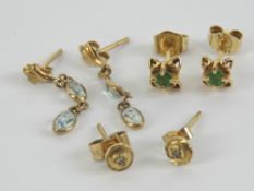 A pair of aquamarine stud earrings each having oval cut aquamarine hanging below yellow metal stud,