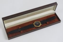 A Gucci wristwatch having yellow metal chapter ring with black dial, strap a/f, with box.
