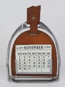 A perpetual desk calendar in the form of a stirrup measuring 18.5cm high.