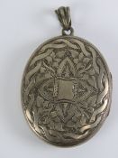 A large white metal locket having rope twist with ivy engraved pattern to front. 6.2cm in length.