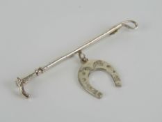 A silver stock pin or brooch in the form of a riding crop with horse shoe under, marked sil,