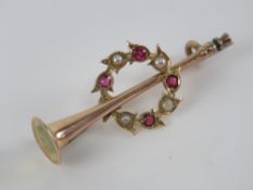 A 9ct gold stock pin brooch in the form of a hunting horn having ruby and pearl wreath surrounding,