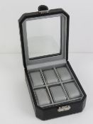 A black leatherette watch box having perspex viewing pane and opening to reveal cushions for six