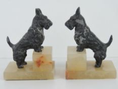 A pair of Scotty dog bookends, each raised over square shaped white onyx stepped base, 16cm high.