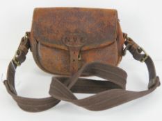 A vintage leather cartridge bag with shoulder strap and brass fittings,