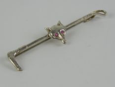 A silver stock pin or brooch in the form of a riding crop having fox mask upon with pink stone eyes,