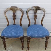 A pair of Victorian mahogany machine carved dining chairs raised over circular turned legs.