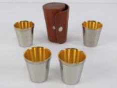 A pigskin leather studded tot cup holder containing four gilded tot cups within,