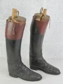 A pair of black and brown leather riding boots, having interior finger pulls,