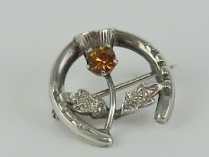 A sterling silver stock pin or brooch having horseshoe and thistle with orange stone upon,
