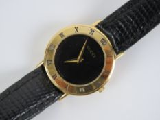 Gucci; a ladies wristwatch having black dial with gold plated chapter ring, marked 3000.2.