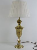 A brass table lamp base of urn form having silk lamp shade, all measuring 60cm high.