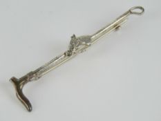 A silver stock pin or brooch in the form of a riding crop with horse head in bridle over,