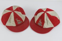 A pair of Harrods red and white peaked team chase caps, each bearing a Stag upon.