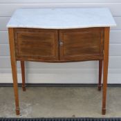 An Edwardian marble top bow fronted double door wash stand, raised over square tapering legs,