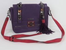 Guess; a purple and hot pink leather handbag with stud work to front and removable tassel,