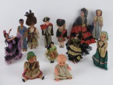 A quantity of assorted vintage dolls in traditional dress including three sleepy eyed dolls.