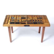 Specimen table with glass top, the centre inset with various items, with Caslon handles and a