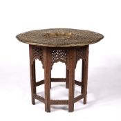 Brass and folding occasional table Indian with carved teak base, 78cm across, 65cm high