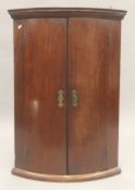 A Georgian mahogany bow front hanging corner cupboard. 87.5 cm high.