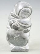 Inuit stone carving of a woman carrying a sack, 17.5cm tall