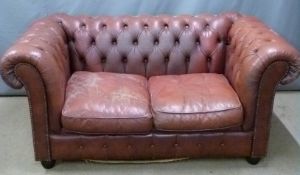 A red leather two seat Chesterfield sofa, W152 x D82 x H76cm