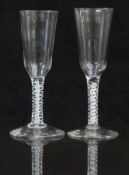 A pair of 18thC drinking glasses both with white double twist stems and long ogee shaped bowls
