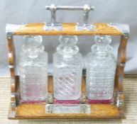 An oak three bottle tantalus with plated fittings, length 37cm