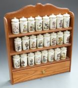 A set of 24 Hummel spice jars on wooden wall mounted shelf unit with drawer below