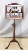 A mahogany duet music stand with fretwork lyre decoration, raised on an adjustable turned support