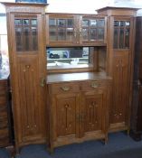 Arts and Crafts oak breakfront dresser, having central double cupboard with bevelled glazed doors,
