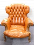 Leather Chesterfield wing back armchair raised on carved mahogany legs, W95 x H100cm