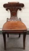 A Victorian mahogany scroll backed hall chair raised on opposing sabre legs