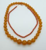 A carved coral necklace threaded on a chain and an amber style necklace