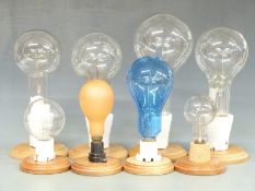 Eight large projector and similar bulbs on wooden display stands, height of largest 35cm