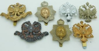 Seven British army 1st King's Dragoon Guards metal cap badges including an all brass example, one by