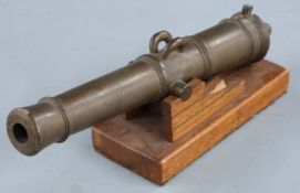 A brass table lighter in the form of a cannon on wooden base, 27.5cm long.
