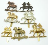 Seven British Army Queen's Royal West Surrey Regiment metal cap badges including officer's