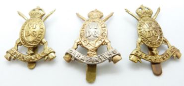 Three British Army 6th Dragoon Guards metal cap badges including an all brass example