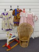 A collection of dolls/ children's dresses together with a small wooden rocking horse and child