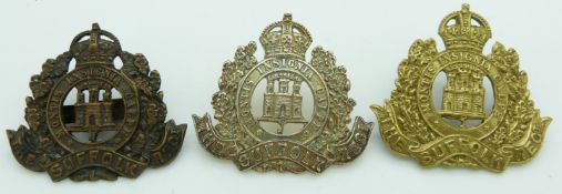 Three British Army Suffolk Regiment metal cap badges including a white metal example with Gaunt