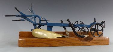 A miniature metal apprentice-made plough with working features, on wooden base, 27cm long.