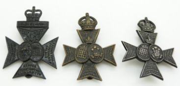 Three British Army Westminster Rifles metal hat badges including an officer's blackened example, one